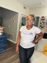 a woman in a purple t - shirt standing in a living room